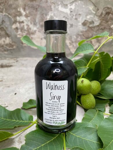 Walnuss Sirup in der Glasflasche mit Schraubverschluss, grüne Walnüsse nur Deko. 